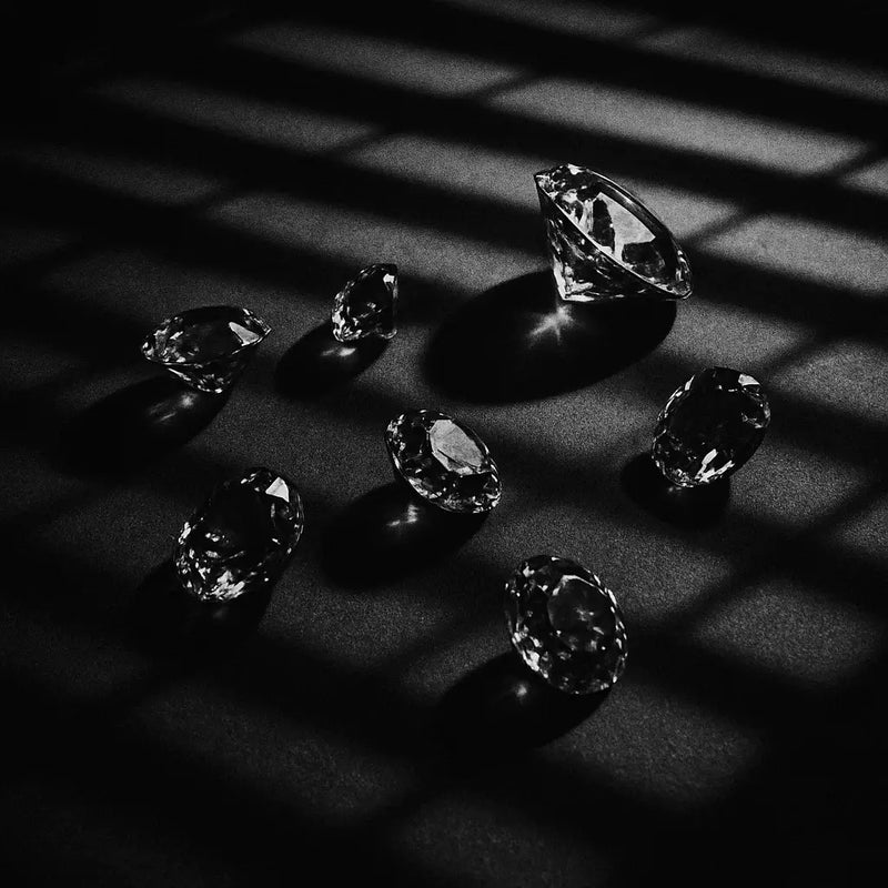 Diamonds arranged on a dark surface with shadows creating a dramatic effect